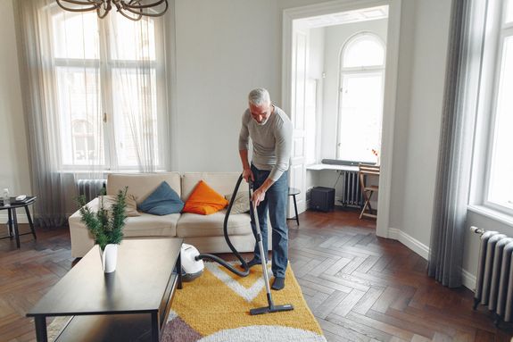 Tall Man Vacuuming a Carpet