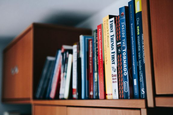 Assorted Books on Brown Wooden Shelf