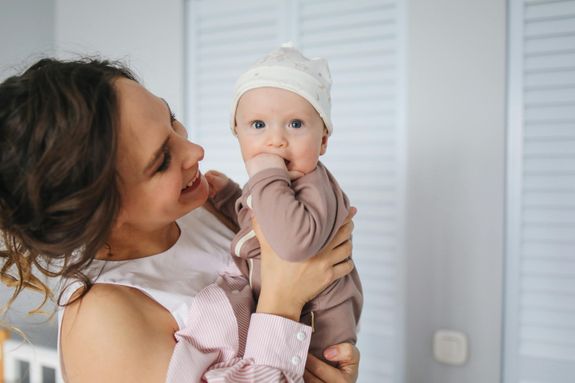 Woman in White and Pink Striped Long Sleeve Shirt Carrying Baby Wearing Brown Onesie