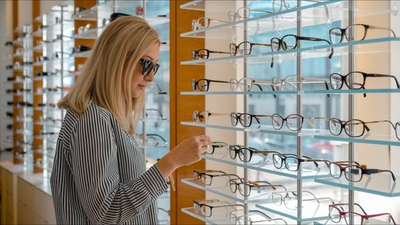 Crop unrecognizable female ophthalmologist showing eyeglasses