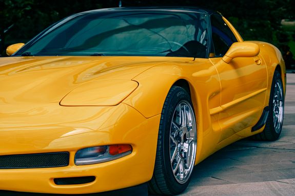 Close-up of a sleek yellow sports car parked outdoors, showcasing its stylish design.