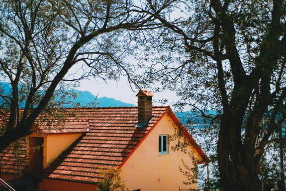 Facade of contemporary house with tiled roof located on tranquil riverside amidst trees on early spring day