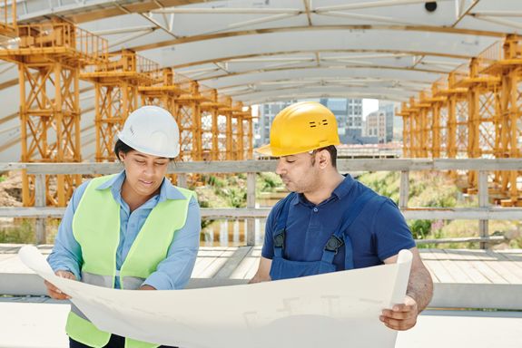 A Man and A Woman with Ppe's Looking at a Blue print
