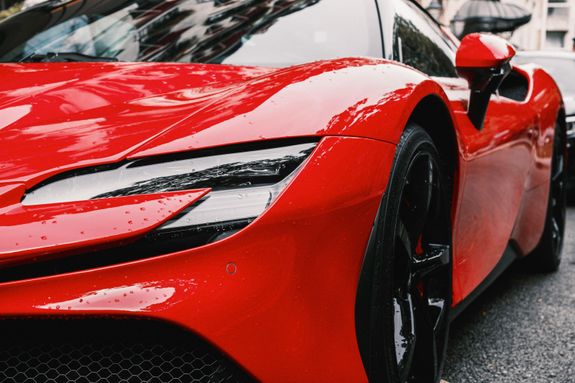 Detailed view of a shiny red luxury sports car exterior showcasing its sleek design and reflections.