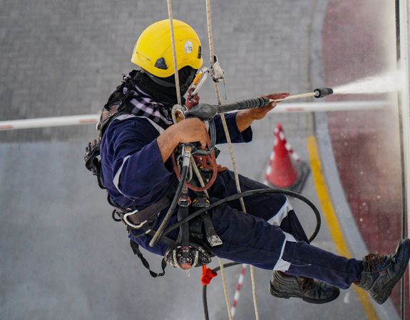 Person in Yellow Helmet Using a Power Spray