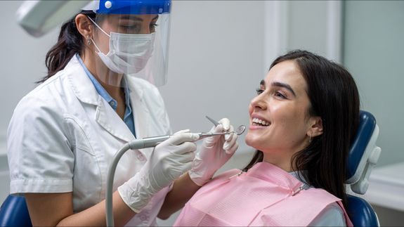 Cheerful stomatologist talking with patient sitting in dental chair