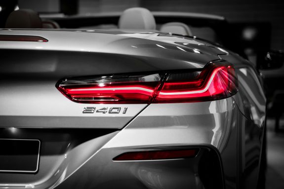 Close-up of a BMW convertible's tail light and emblem, showcasing luxury design.