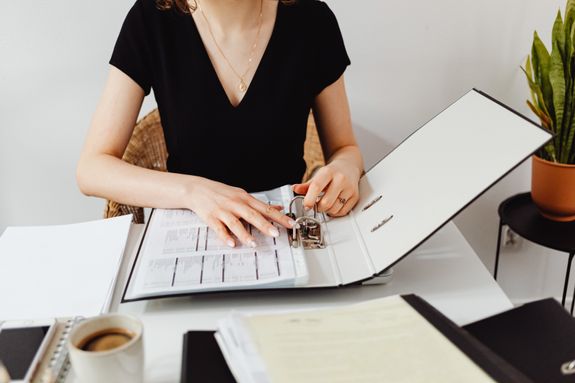 Photo of a Woman Putting Paper on a Binder