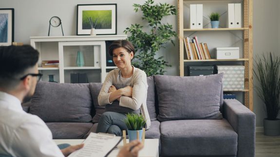 A woman sitting on a couch talking to a man