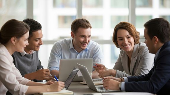 Crop anonymous ethnic woman passing clipboard to office worker with laptop during job interview