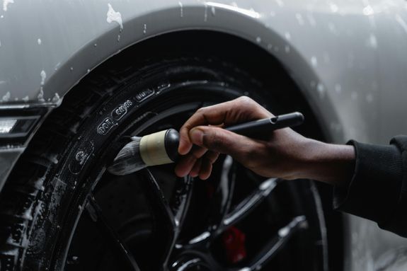 A Close-Up Shot of a Person Brushing the Wheel of a Car