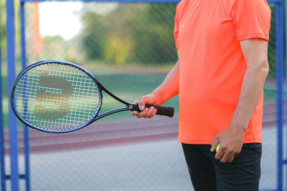 Tennis player standing with racket and ball