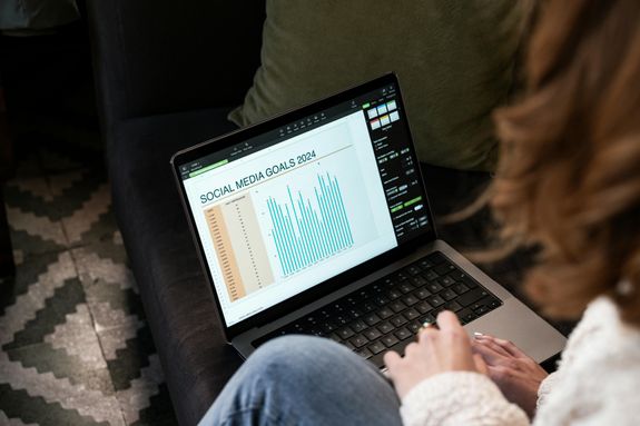 Woman Sitting on a Sofa with a Laptop Displaying a Chart 