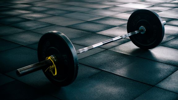 From above of professional ethnic constructor helping young plus size woman working out with rowing machine in sport club