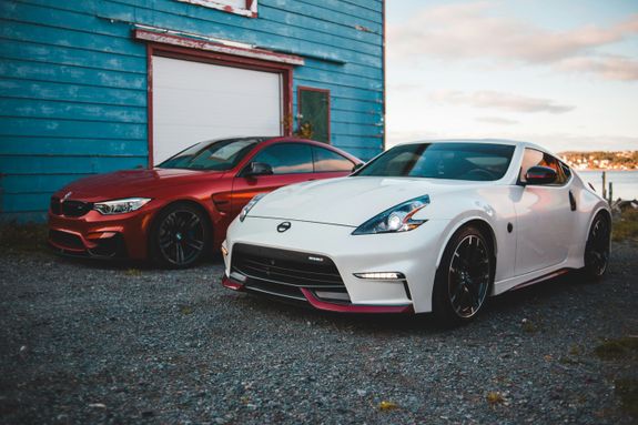 Trendy sports autos parked near lake shore in countryside at sunset