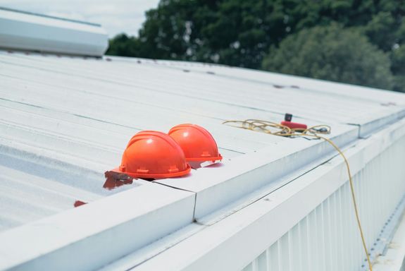 Red hard hats and safety equipment on a metal roof, emphasizing construction safety.