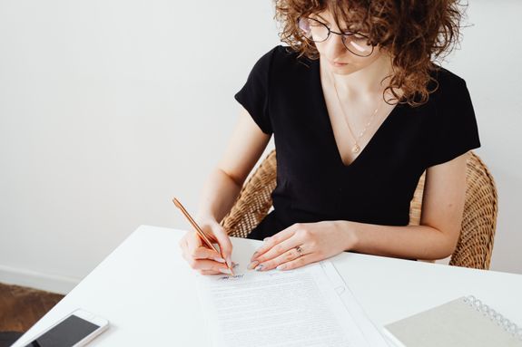 Woman in Black Shirt Signing on White Paper