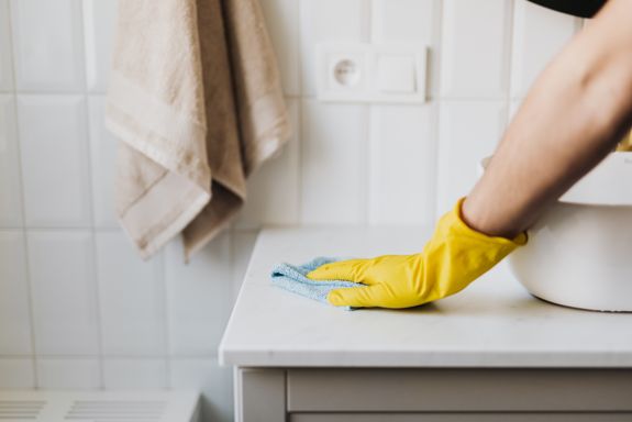 Crop housewife cleaning surface near sink