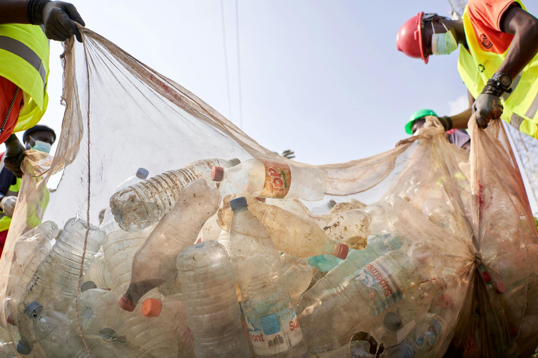Low Angle Shot of People Holding a Garbage Bag Full of Plastic Bottles