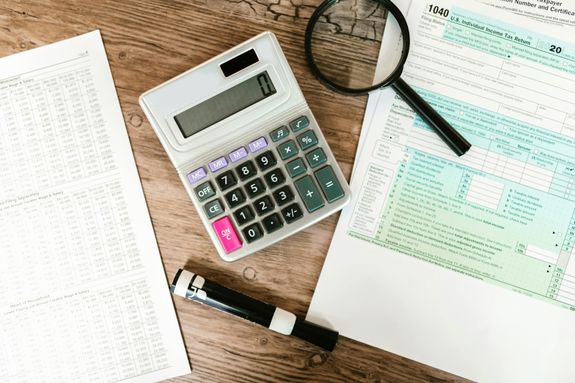 Tax forms with calculator and magnifying glass
