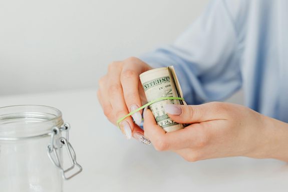 Close-Up Shot of a Person Using Rubber Band to Tie Up the Paper Money