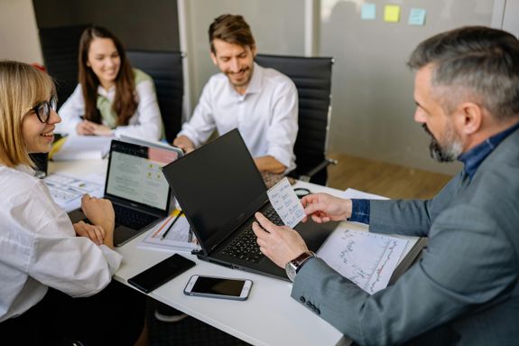 Business team discussing strategies with laptops and documents at a modern office table.