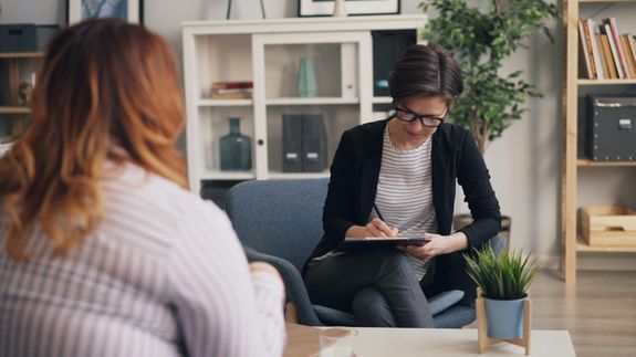 A woman sitting in a chair and talking to another woman