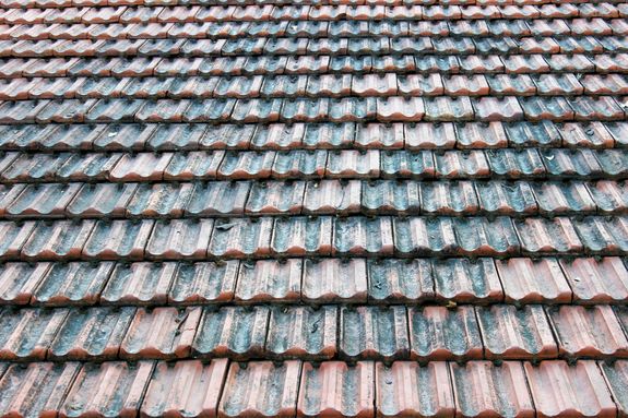 Close-up view of a rustic terracotta roof, showcasing intricate tile pattern and texture.