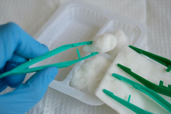 A Close-Up Shot of a Person Wearing Latex Gloves Using a Disposable Dressing Set