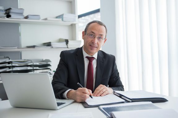 A Man in Black Suit Looking while Holding a Pen