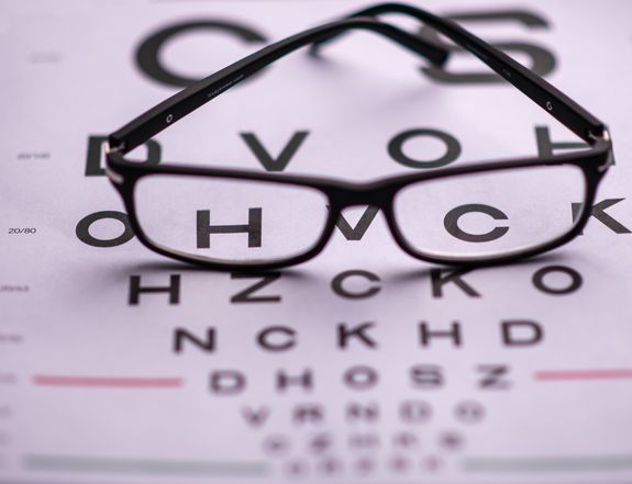 From above of classic eyeglasses placed on eye chart with letters in ophthalmologist room