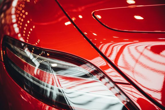 Detailed view of a shiny red car's tail light with bokeh reflections.