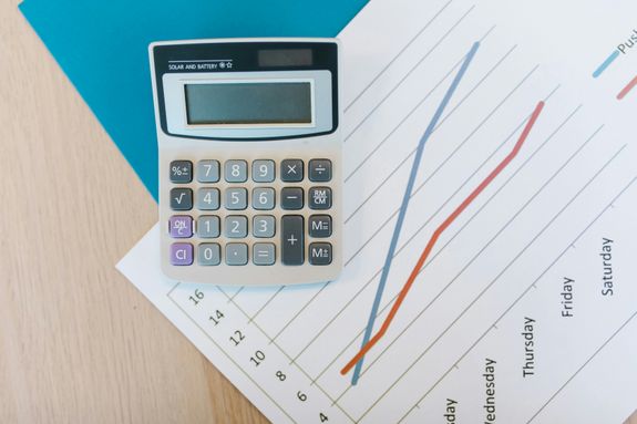 Top view of calculator and graph paper on office desk, perfect for business themed visuals.