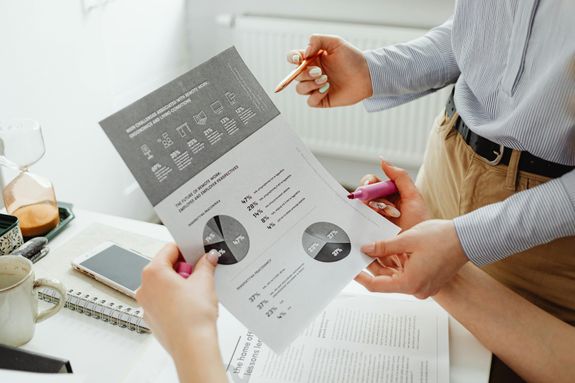 A close-up view of two colleagues analyzing business graphs and charts together.