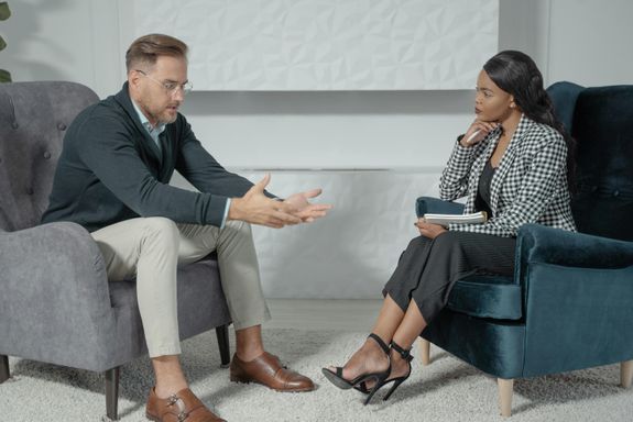 A business conversation between a man and woman in a modern office setting, focusing on engagement and communication.