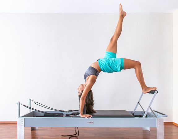 Side View of a Woman in Activewear Doing Pilates Reformer Exercise