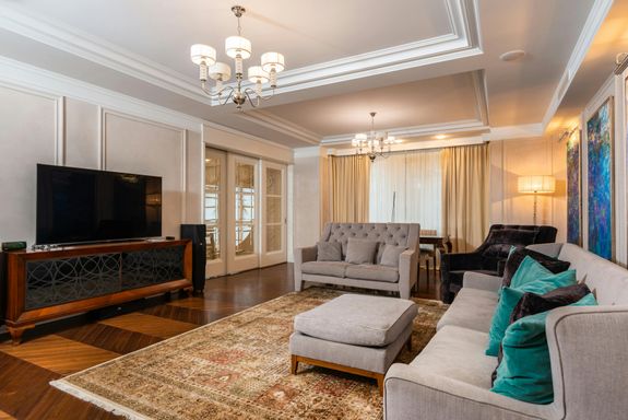 Spacious modern living room featuring elegant sofas, chandelier, and TV setup.