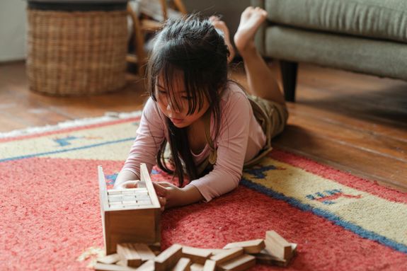 Girl in White Long Sleeve Shirt Playing With Brown Wooden Blocks