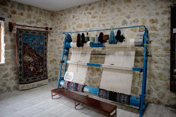 A rug is displayed in a room with a stone wall