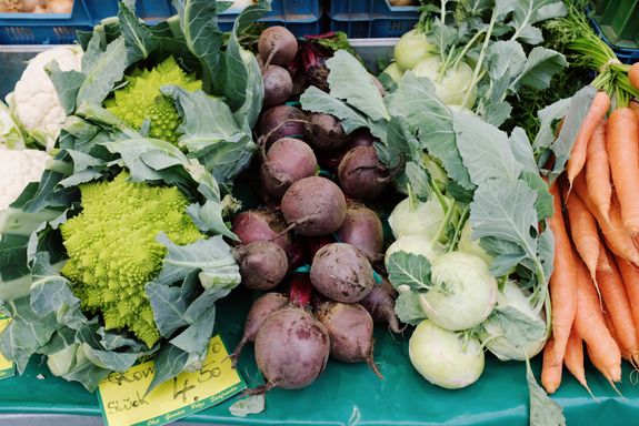 From above set of fresh colorful vegetables placed on table with price tag in grocery market at daytime