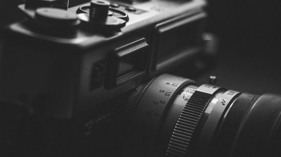 Detailed monochrome close-up of a vintage camera lens, highlighting aperture settings and classic design.