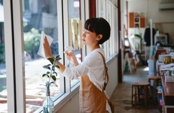 Woman Wearing Apron Cleaning Window Glass