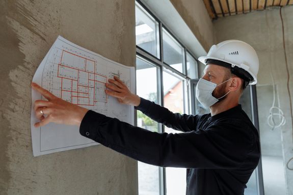 A Man in Black Long Sleeve Shirt Holding White Paper on Concrete Wall