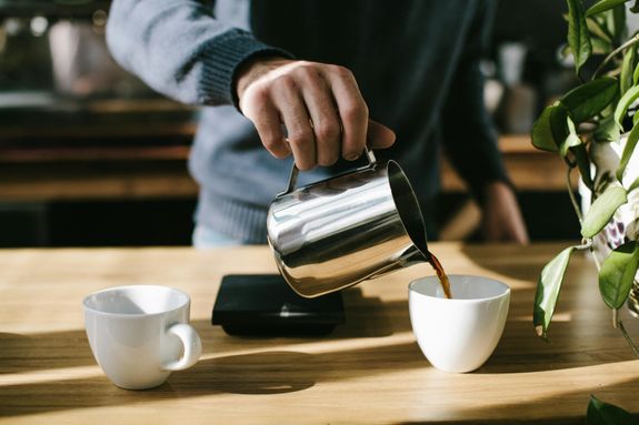 Person Pouring Coffee in White Ceramic Mug