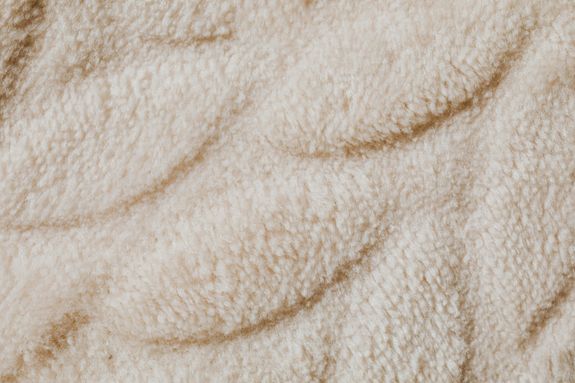 Detailed close-up of a plush beige carpet showcasing its soft fabric texture.