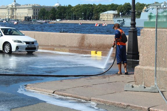A man is washing the street with a hose