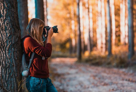 A woman taking photos in an autumn forest, perfectly capturing the beauty of nature.