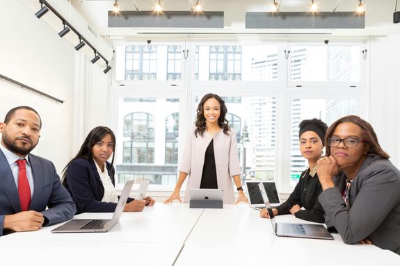 A diverse group of professionals having a meeting in a modern office setting with large windows.