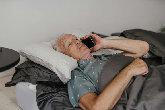 Man Lying on Bed Holding Black Smartphone