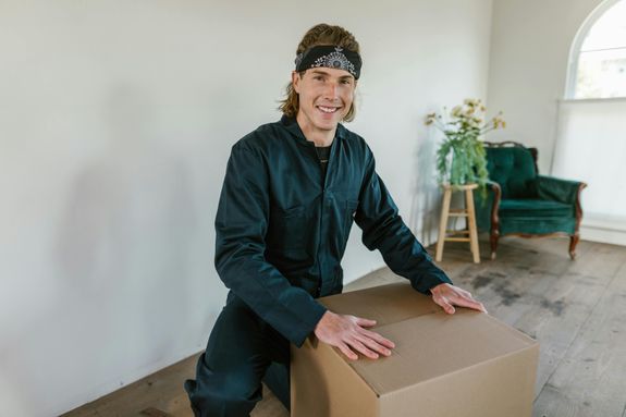 Man in Black Zip Up Jacket and Blue Denim Jeans Sitting on Brown Wooden Table